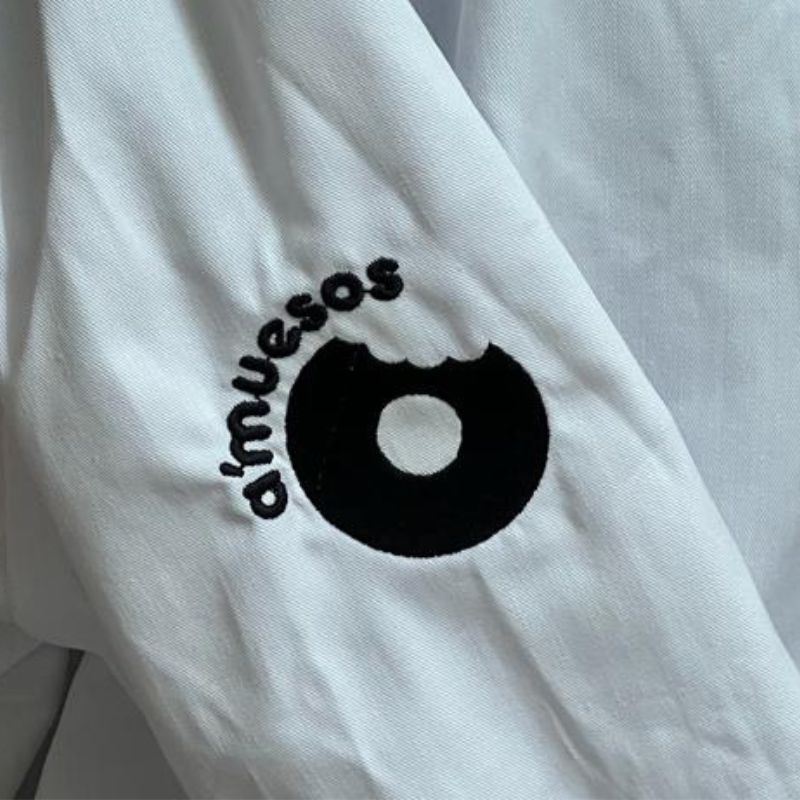 Detalle de bordado de chaqueta de cocina con logotipo en manga en hilo negro - amuesos - paula berdiel - inmenta estudio creativo - huesca